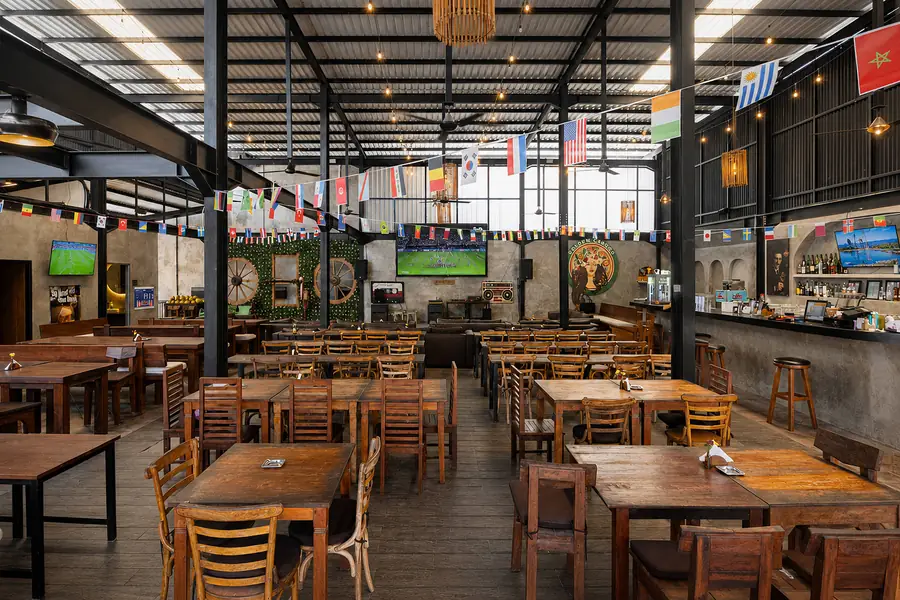 The main hall at Garden Canggu with world flags, long communal tables and the bar